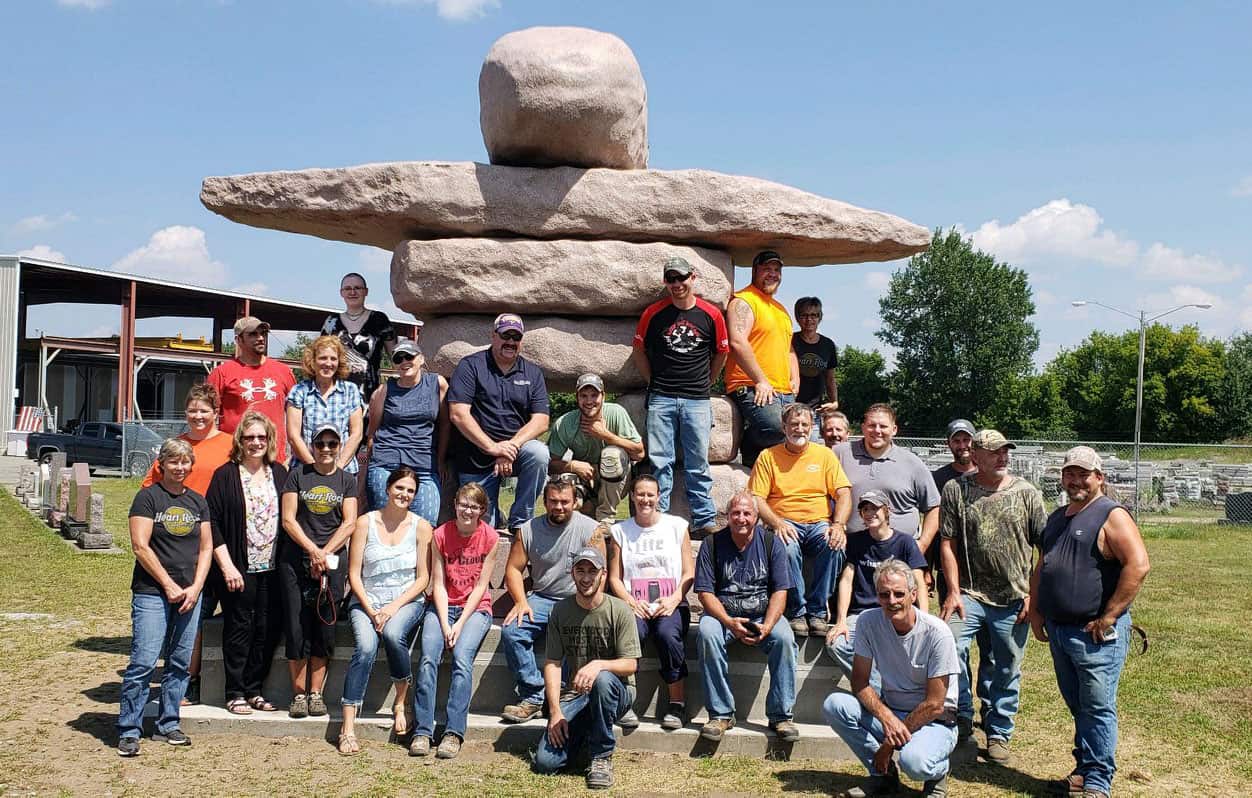 The team posing for the camera in front of a stone man statue