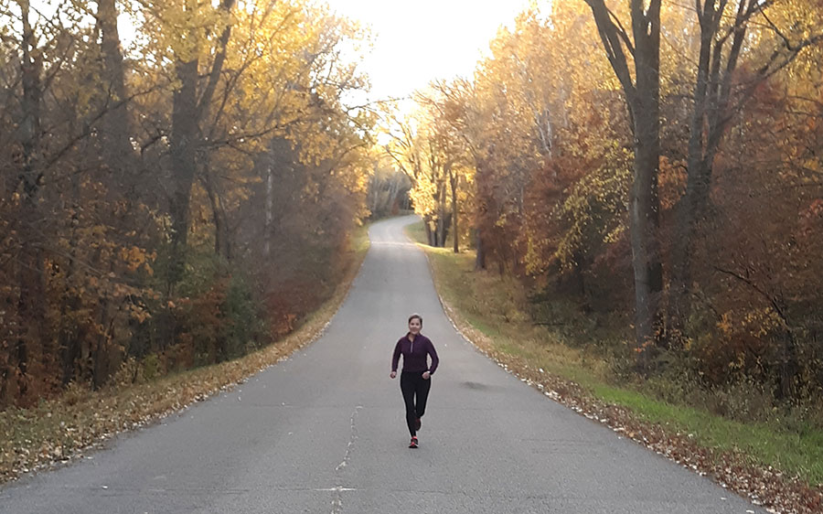 a runner on an empty paved road through the trees